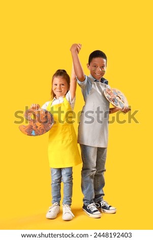 Cute little children with faces in paints holding hands on yellow background