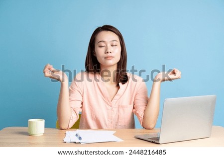 Photo of young Asian businesswoman on blue background