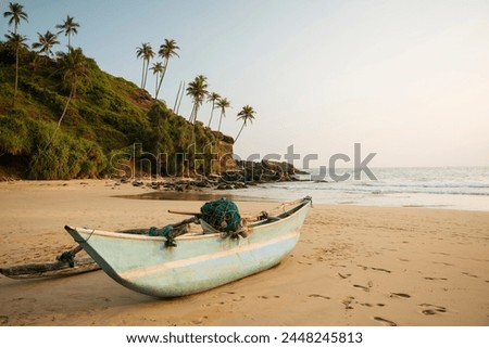 Traditional wooden boat on Talalla Beach at dusk, South Coast, Sri Lanka, Asia Royalty-Free Stock Photo #2448245813