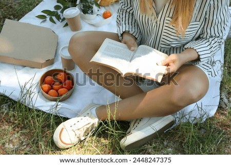 A girl on a picnic reads a book
