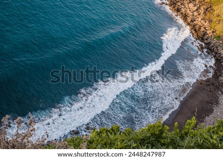 Vegetation and aerial view of water bursting into black volcanic sand in the bathing area of Foz das Coelhas, São Miguel - Azores PORTUGAL Royalty-Free Stock Photo #2448247987
