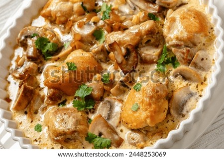 chicken thighs in a creamy mushroom garlic sauce with herbs and parmesan cheese in white baking dish, dutch angle view, close-up Royalty-Free Stock Photo #2448253069