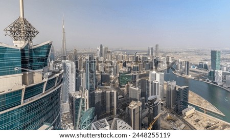 Panoramic aerial view of business bay towers in Dubai at evening timelapse. Rooftop view of some skyscrapers, canal and new towers under construction.