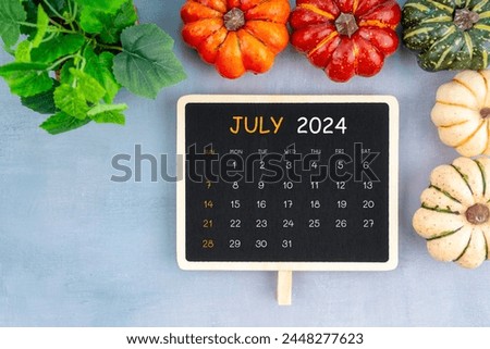 View from above to simple July 2024 calendar decorated with pumpkin and green leaves.