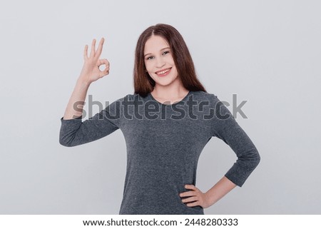 young caucasian beautiful woman in grey sweatshirt showing ok gesture