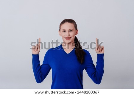 young caucasian attractive woman in blue sweatshirt pointing up with fingers