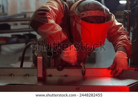 A welder in a mask welds stainless steel parts.