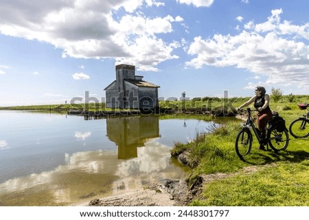 Woman cycles on an e-bike through the Po Delta in Northern Italy ( Valley of Comacchio ) Royalty-Free Stock Photo #2448301797