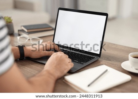 Young man watching webinar at table in room, closeup