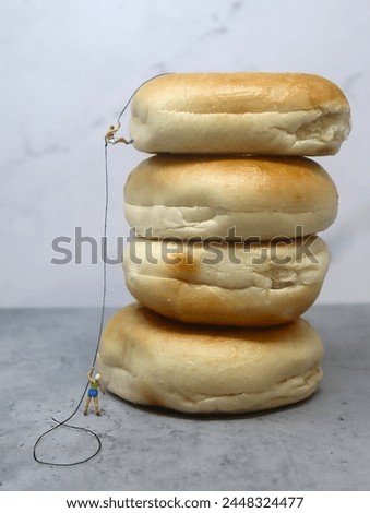 Miniature Climber Rappeling Down Pile of Fresh Bagels. Royalty-Free Stock Photo #2448324477