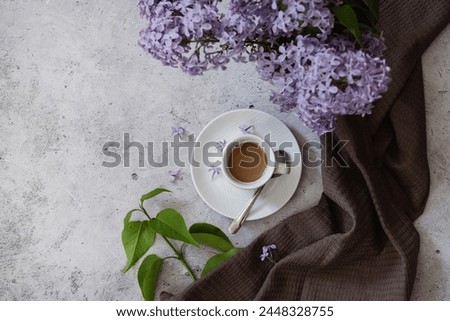Spring time. The concept of Good morning. A fancy violet coffee mug, an old book, a straw hat, and purple lilac. Beautiful still life.