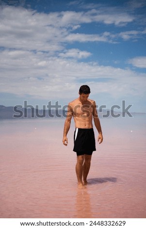 Man walking in shallow Pink Salt Lake in Utah near Salt Lake City.  Located in the Southwest of the USA.
