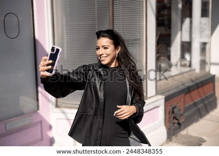 Young woman in the city with smart phone taking a selfie