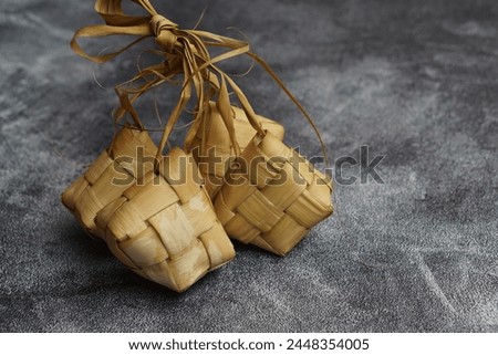 Close up view of Ketupat, an Indonesian traditional cuisine very popular during Hari Raya Idul Fitri served on a wooden table. This is made of the white rice, usually served with opor ayam on Ied day. Royalty-Free Stock Photo #2448354005