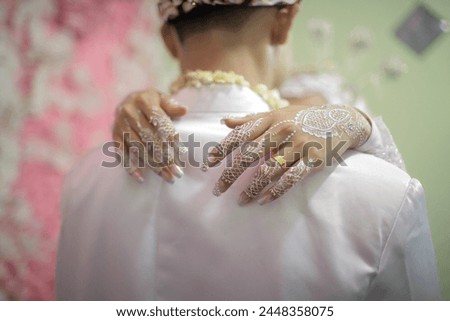Close up of henna decorated bride's hands hugging groom against blurred background