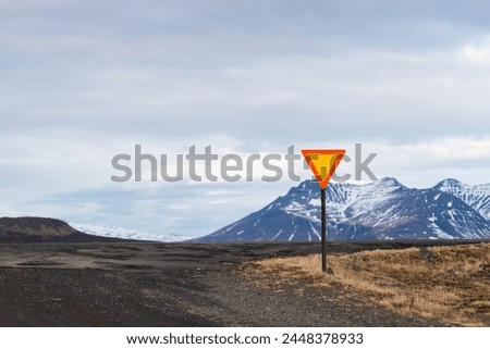 Triangle traffic sign warning stand alone for driving road trip in Iceland travel with snowy mountain and a vast sky landscape