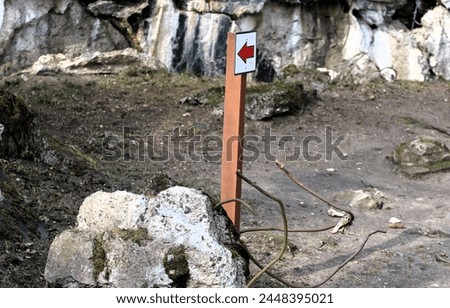 a wooden sign post with a red arrow next to concrete block wires