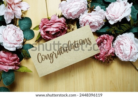 Congratulations text message on paper card with flowers border frame on wooden background