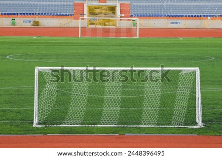 Football field with goal and tablo on blue sky