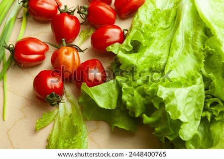 Fresh lettuce leaves and tomatoes on wood table, top view. Salad background from fresh vegetable for poster, calendar, post, screensaver, wallpaper, postcard, cover, website. High quality photography