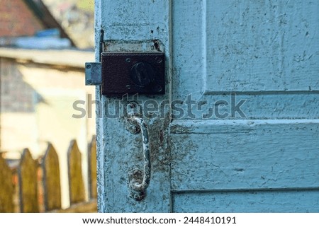 one old brown mechanical square iron mortise reliable lock on a wooden dirty white door during the day on the street Royalty-Free Stock Photo #2448410191