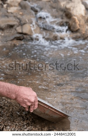 Searching for gold with an iron pan in a riverbed. Gold panning Royalty-Free Stock Photo #2448412001
