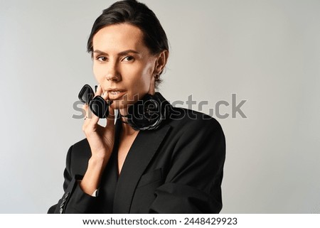 A stylish woman in sunglasses confidently poses in a sleek black suit