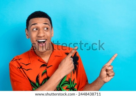 Photo of excited impressed guy dressed print shirt looking showing two fingers empty space isolated blue color background