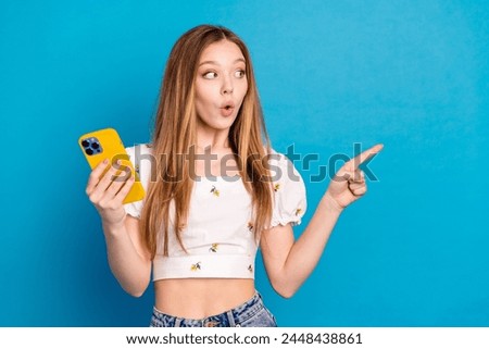 Photo of girl hold cell phone look empty space feel impressed isolated blue color background