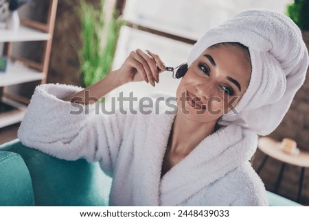 Photo portrait of pretty young girl apply massager roller flawless skin head wrapped towel dressed bath robe beauty routine home concept