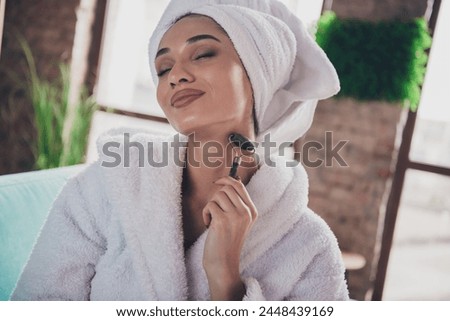 Photo portrait of attractive young woman closed eyes neck roller massager face wrapped towel dressed bath robe home interior enjoy weekend