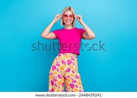 Photo portrait of lovely young lady touch sunglass summer vacation dressed stylish pink clothes isolated on blue color background