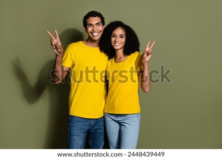 Photo of two young people show v-sign empty space wear t-shirt isolated on khaki color background
