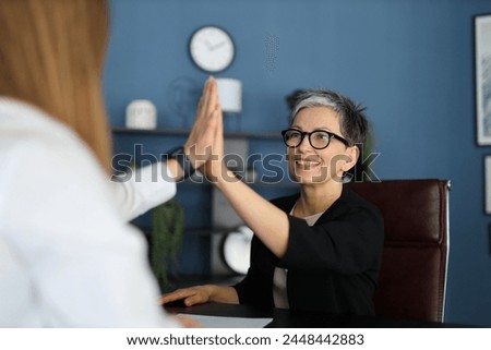 In the office, two businesswomen exemplify teamwork and leadership through confident cooperation and successful communication. Royalty-Free Stock Photo #2448442883