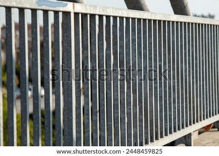 Close-up view of the steel structure of a modern bridge. Close-up of metal fence on the street. Detail of a steel bridge with blue sky in the background. Royalty-Free Stock Photo #2448459825