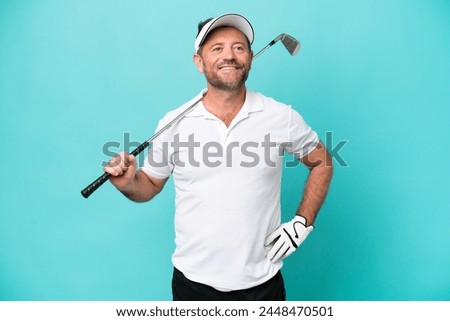 Middle age caucasian golfer player man isolated on blue background posing with arms at hip and smiling