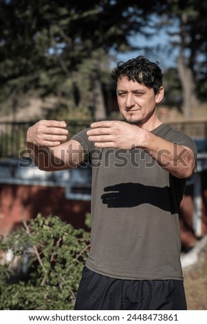 A middle-aged Caucasian man adopts the static posture of Tree Hugging, a crucial technique in Chi Kung practice. Royalty-Free Stock Photo #2448473861