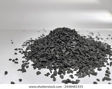 Black crumb rubber granules for jogging track or playground, uniform granule shape, white blur background, close up, side view Royalty-Free Stock Photo #2448481555