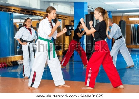 Pair of young women practicing new karate moves during group training at gym