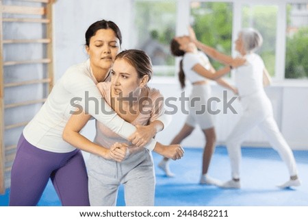 Self-defense class - woman learns to fight back an attacking man under the guidance of a trainer