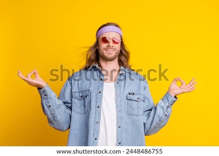 Portrait of cool young man meditate wear denim shirt isolated on yellow color background