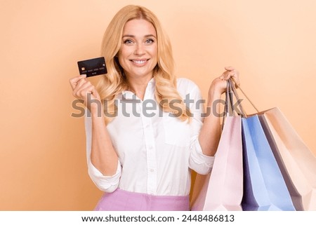 Photo of excited pretty woman wear white shirt rising bank card bargains isolated beige color background
