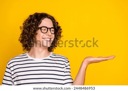 Photo portrait of pretty teen male hold look excited empty space dressed stylish striped outfit isolated on yellow color background