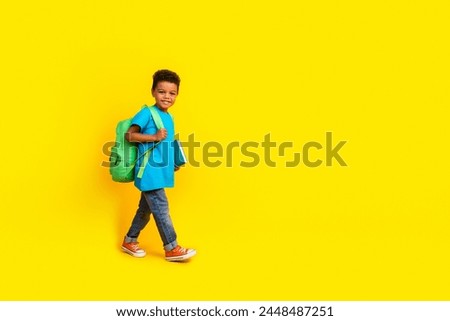Full body photo of mixed race multiethnic multinational child dressed blue t-shirt bag book go empty space isolated on yellow background Royalty-Free Stock Photo #2448487251