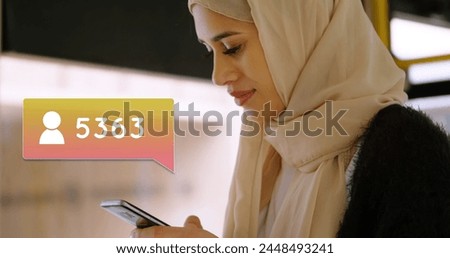 Close up of a Muslim wearing a hijab while texting on her phone. Beside her in the foreground is a digital image of a message bubble with a follower icon increasing in count