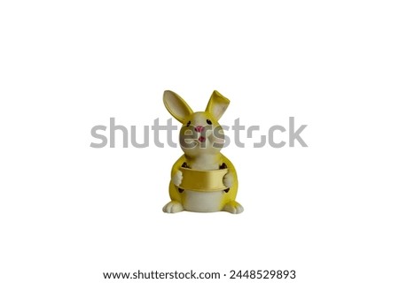 Closeup of Yellow rabbit plastic piggy bank holding a gold sign isolated on white background at Thailand.