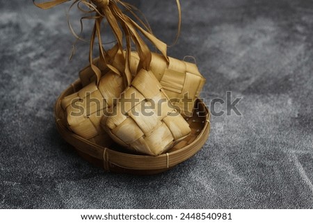 Close up view of Ketupat, an Indonesian traditional cuisine very popular during Hari Raya Idul Fitri served on a wooden table. This is made of the white rice, usually served with opor ayam on Ied day. Royalty-Free Stock Photo #2448540981