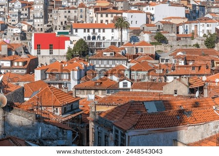 Cityscape of Porto with old ancient buildings, orange roofs and gray walls under construction. A vertical photo.