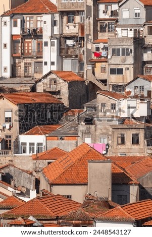 A rough and raw view of the city Porto with old ancient buildings, orange roof tops and gray walls. A vertical photo.