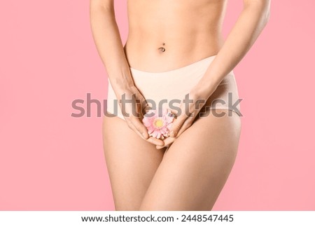 Young woman in panties with beautiful flower on pink background